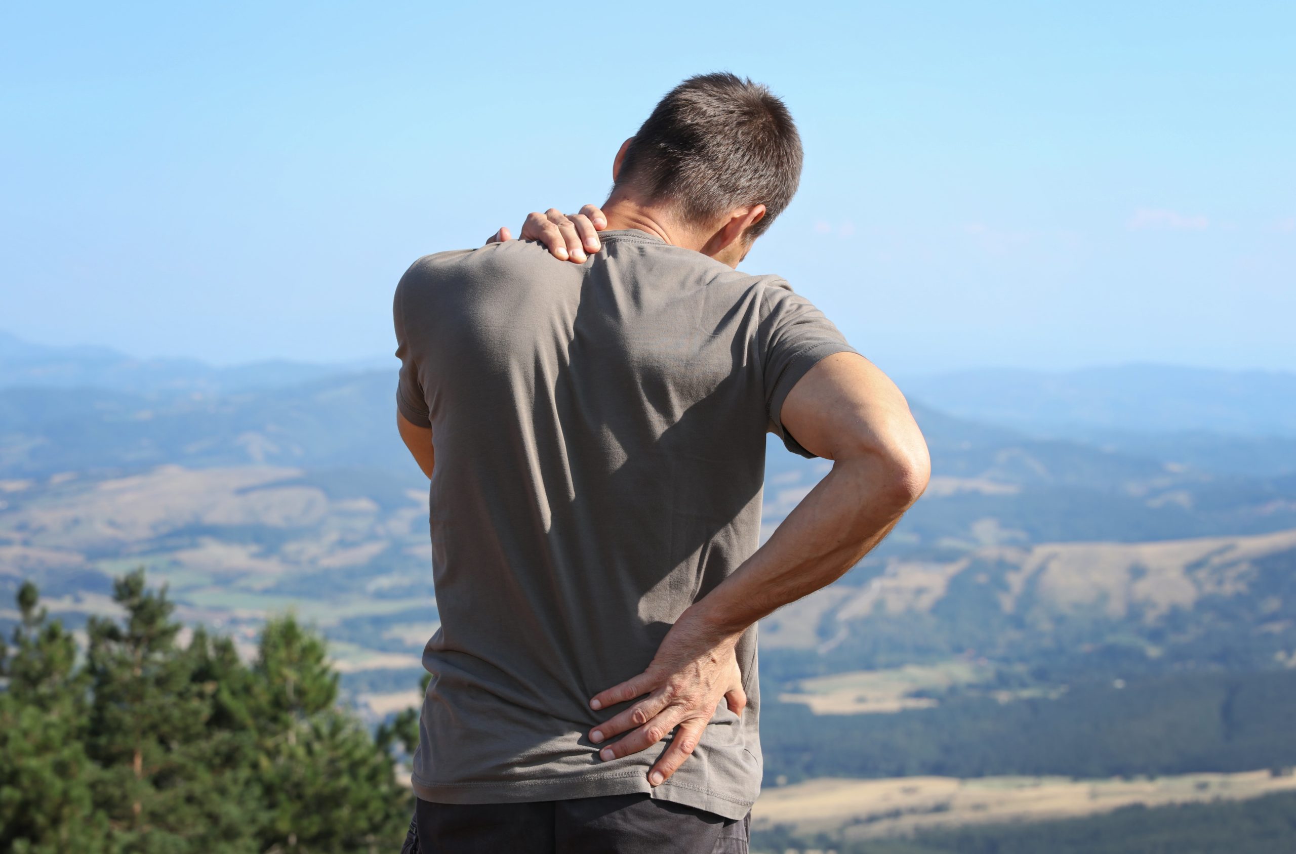 man holding his neck and back for pains